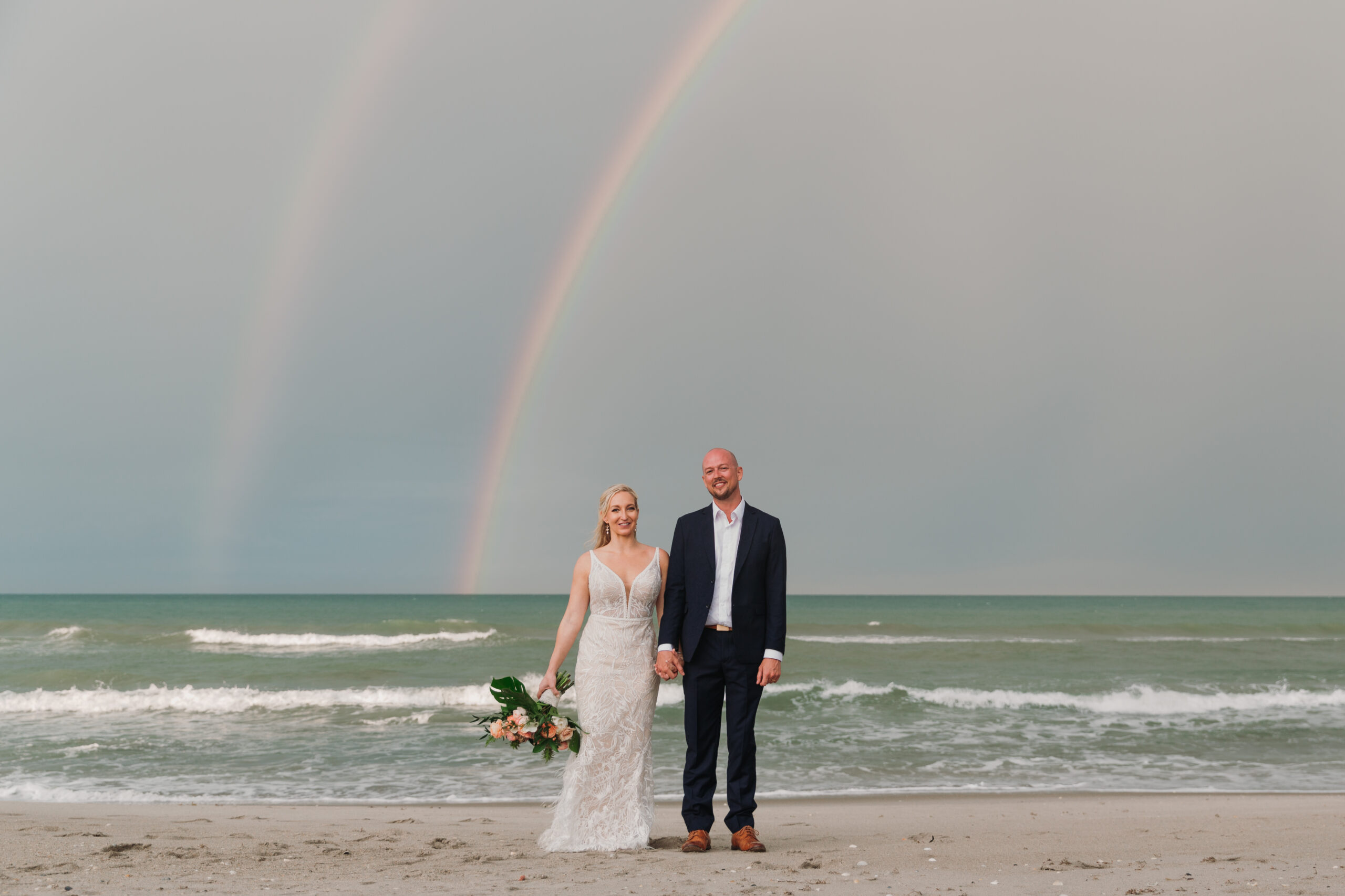 Wedding couple married under a rainbow by the ocean