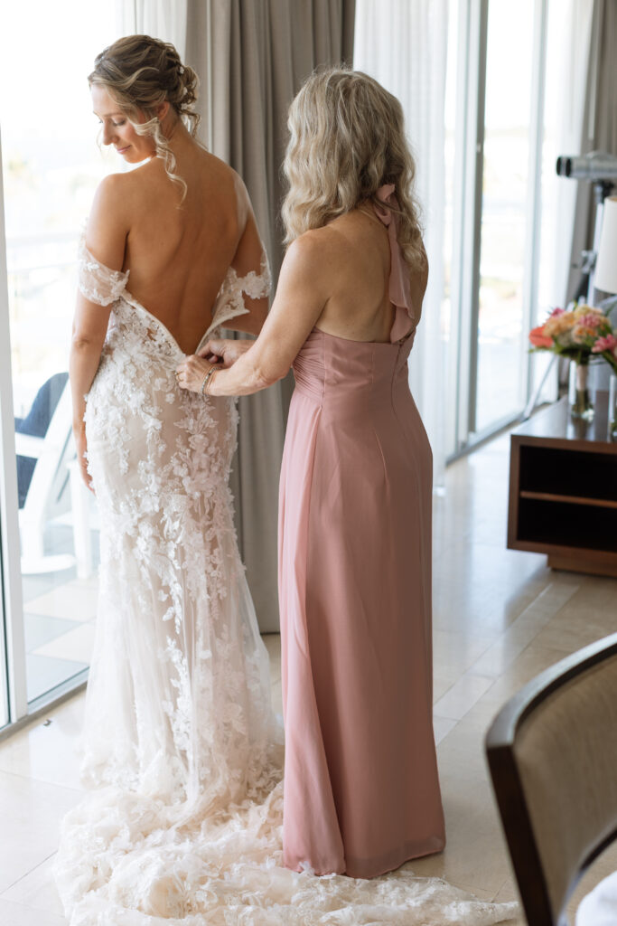 Bride's mom helping bride in her wedding gown