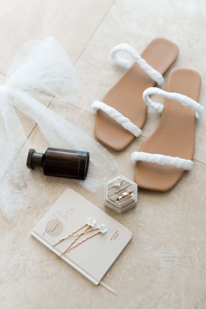 Close-up of the bride's wedding details, shoes, vow book, and perfume at The Reefhouse in Key Largo, with soft sunlight filtering through the windows, captured by The Deans Photography