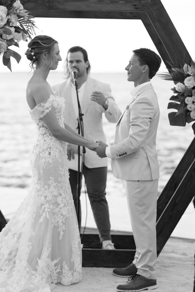 Bride and groom exchange vows during a romantic beachfront wedding ceremony at The Reefhouse in Key Largo, Florida, with the ocean as their backdrop.