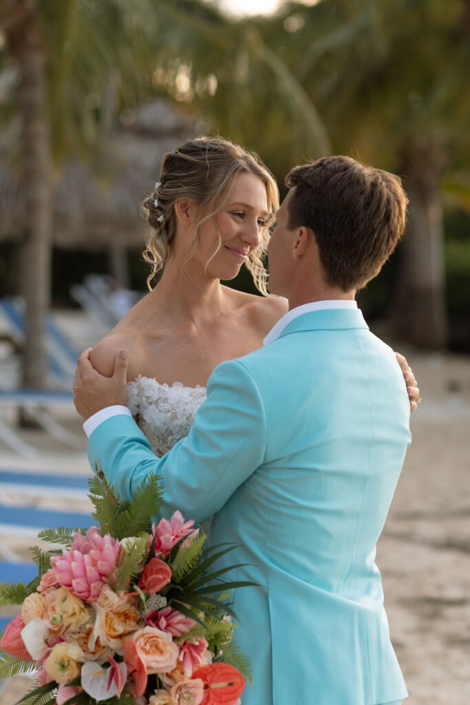 Bride and groom embrace during their wedding photoshoot at The Reefhouse, with lush tropical greenery and the calm waters of the Florida Keys surrounding them.