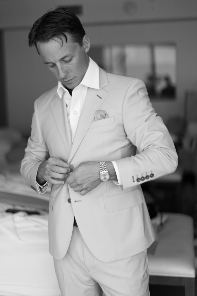 Close-up of the groom adjusting his suit at The Reefhouse, captured by The Deans Photography