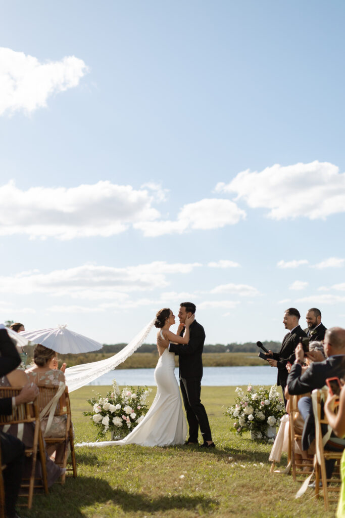 Outdoor wedding ceremony at Lavender on the Lake, photographed by The Deans Photography, with the couple exchanging vows by the serene lake surrounded by beautiful lavender fields.