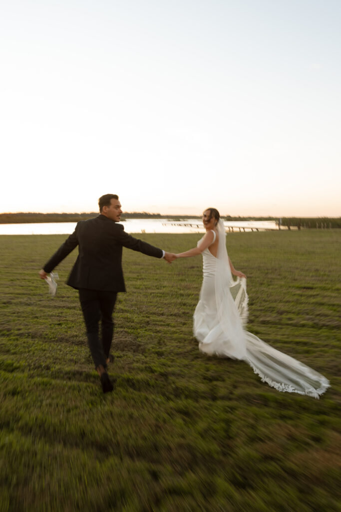 Bride and groom walking through the lavender fields at Lavender on the Lake, captured by The Deans Photography, with vibrant lavender blooms and tranquil lake views.