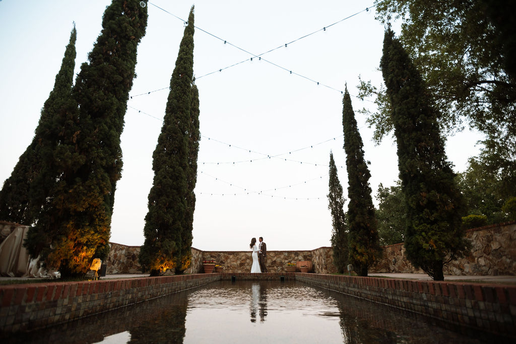 Bride and groom captured by The Deans Photography at Bella Collina, with the stunning Tuscan-style architecture and panoramic countryside in the background.