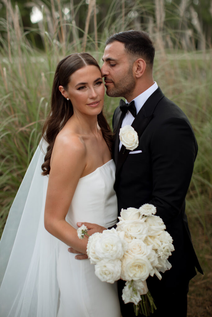 Bride and groom posing for a stunning wedding portrait at Disney's Four Seasons Resort Orlando, captured by The Deans Photography, with elegant architecture and manicured gardens in the background.