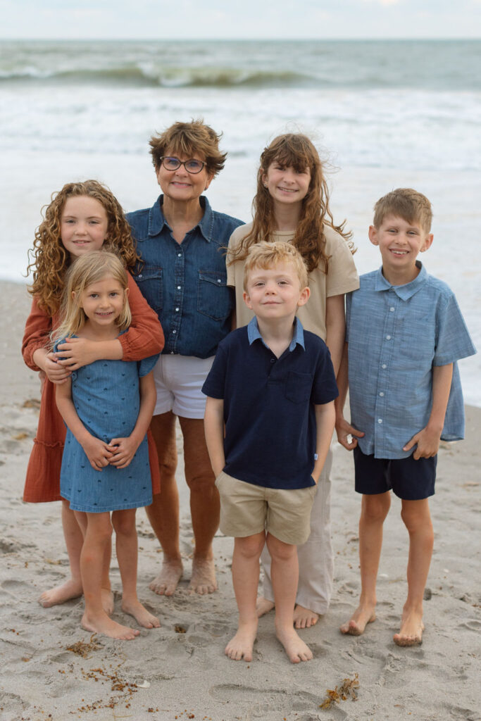 Grandparent interacting with grandchildren at the water’s edge on Melbourne Beach during a family photo session.