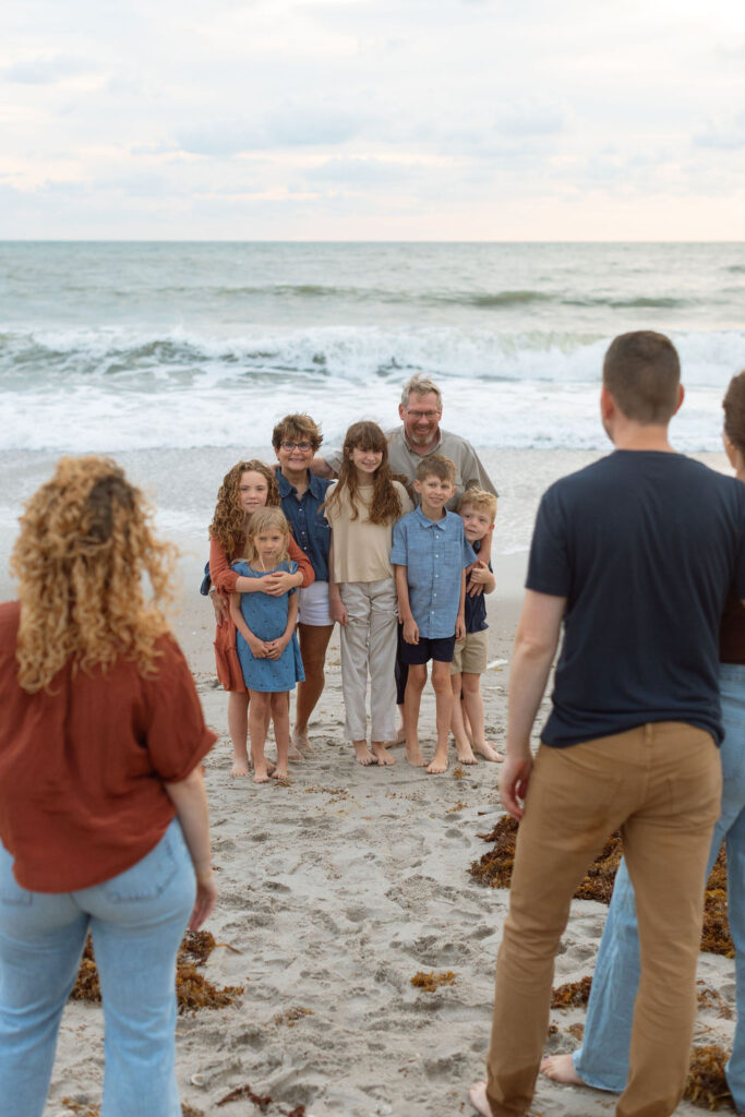 Grandparent interacting with grandchildren at the water’s edge on Melbourne Beach during a family photo session.