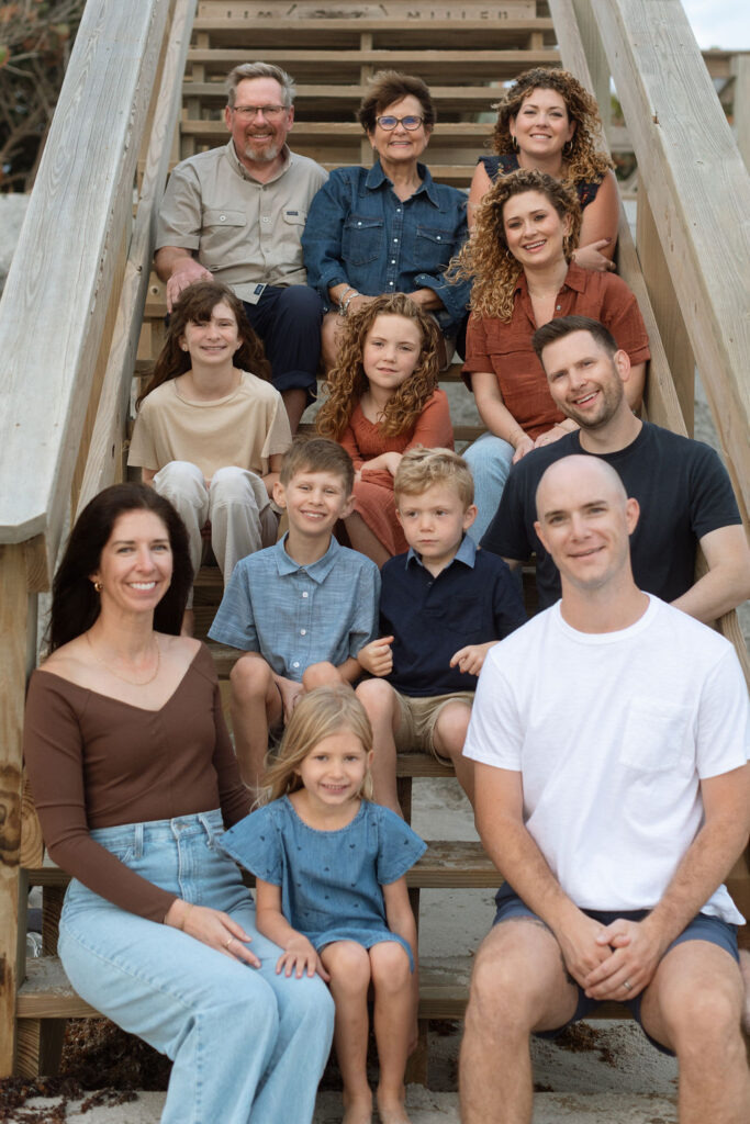 Family of 12 sitting together on the boardwalk of Melbourne Beach, enjoying the sunrise and each other’s company