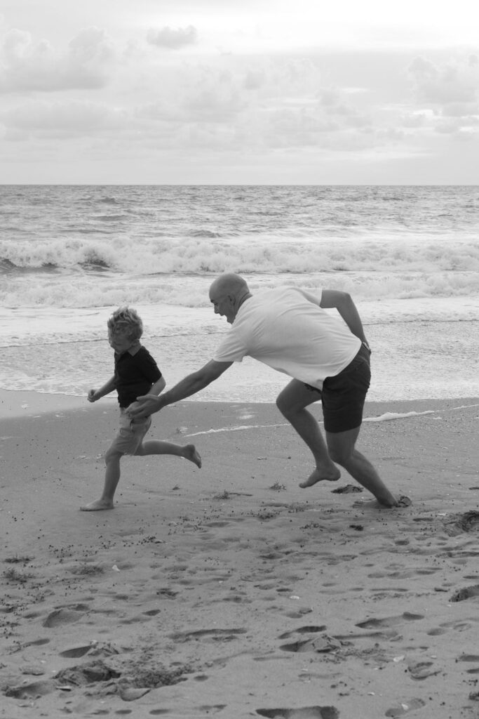 Dad and son playing in the sand on Melbourne Beach during a family photo session at sunrise.