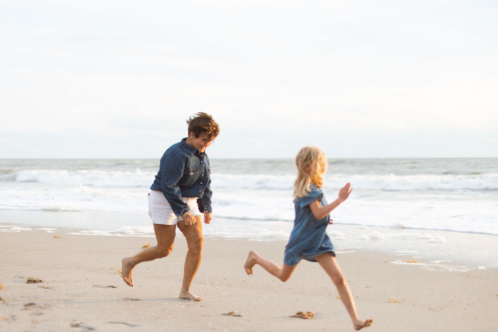 Grandparents and grandchildren playing in the sand on Melbourne Beach during a family photo session at sunrise.