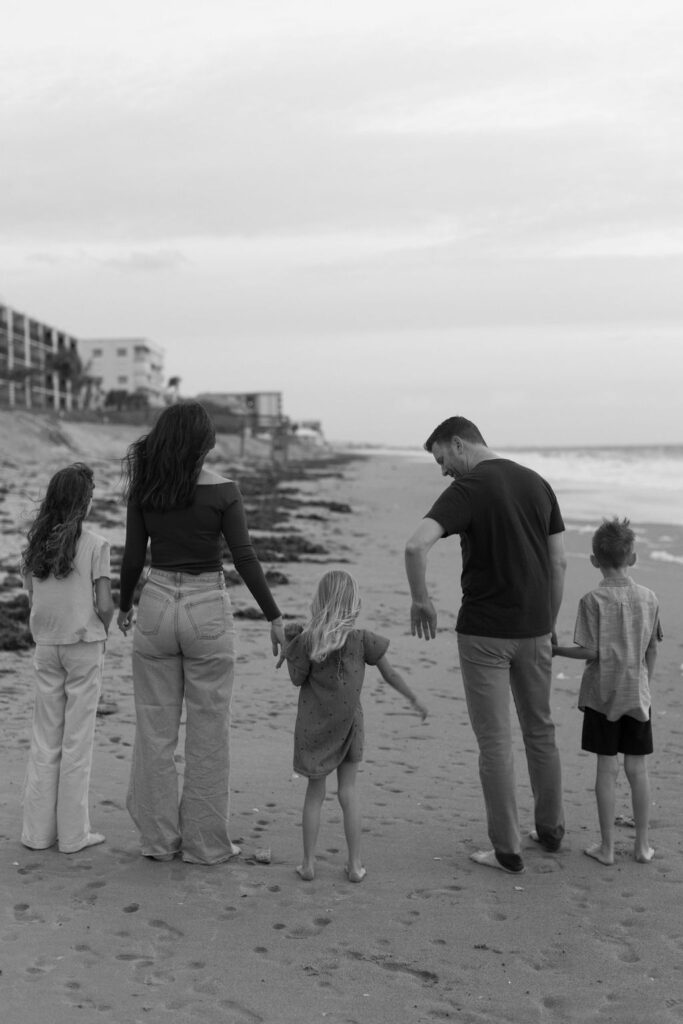 Parents having a quiet, tender moment with their children on Melbourne Beach during a family photography session.