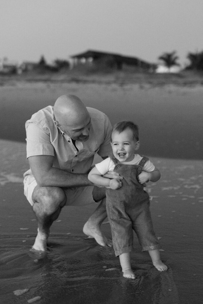 Father holding his toddler on Cocoa Beach at sunrise, creating memories during a family photography session.