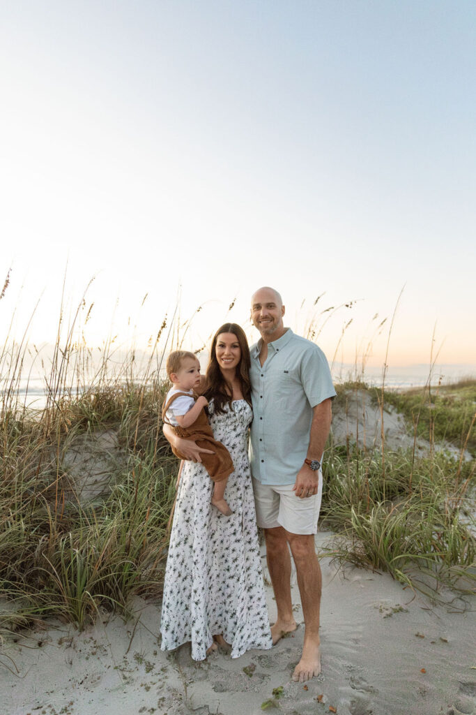 Parents sharing a loving embrace with their toddler on Cocoa Beach, during a sunrise family photography session.