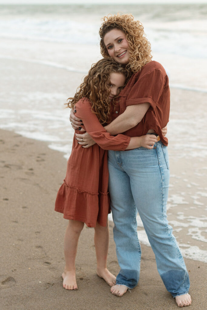 candid photo of aunt and niece walking on the sand in melbourne Beach.