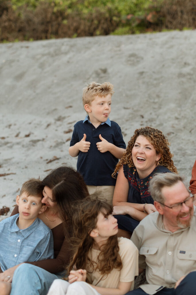 Candid family photo of 12 family members gathered together on Melbourne Beach during sunrise, enjoying the beach