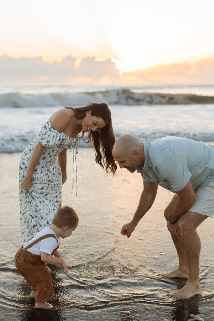 Parents playing with their toddler in the waves, located in Cocoa Beach.