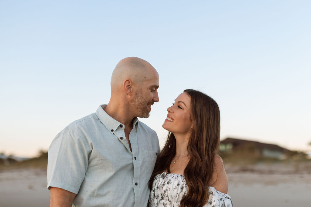 Parents holding hands with their toddler on Cocoa Beach at sunrise, creating memories during a family photography session.