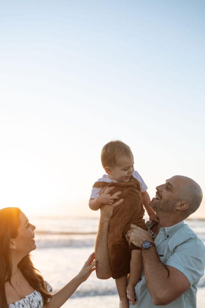 Family of three looking out over the ocean during a family beach session on Cocoa Beach at sunrise
