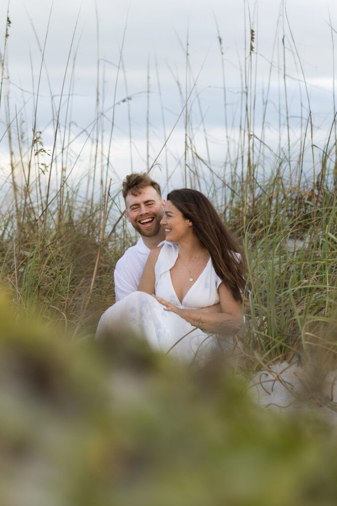 Candid photo of couple laughing on Cocoa Beach at sunset, captured naturally by The Deans Photography during golden hour.