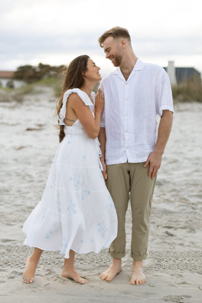 Engaged couple walking hand-in-hand along Cocoa Beach at sunset, captured by The Deans Photography.