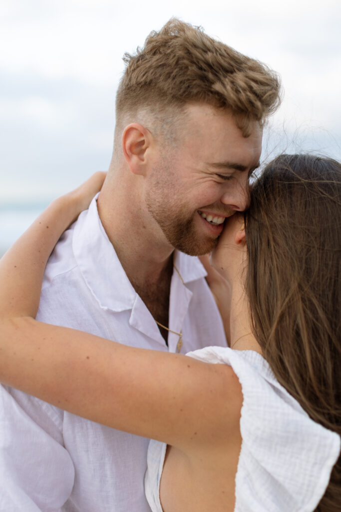 Candid photo of couple laughing on Cocoa Beach at sunset, captured naturally by The Deans Photo during golden hour.