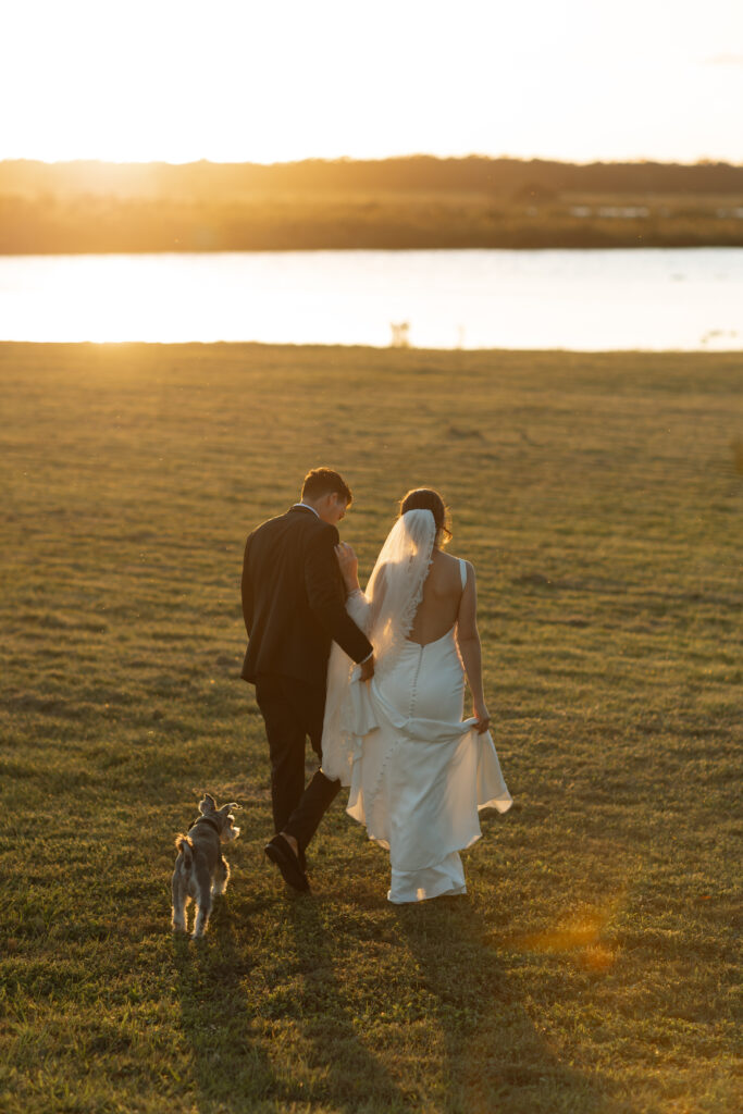 Intimate moment of couple and their sweet dog walking towards the sunset, photographed by The Deans Photography.