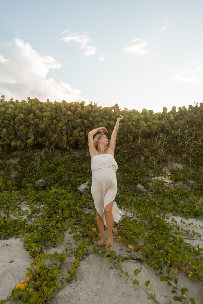 Pregnant woman in a beautiful flowing dress during outdoor maternity photo session in Central Florida.