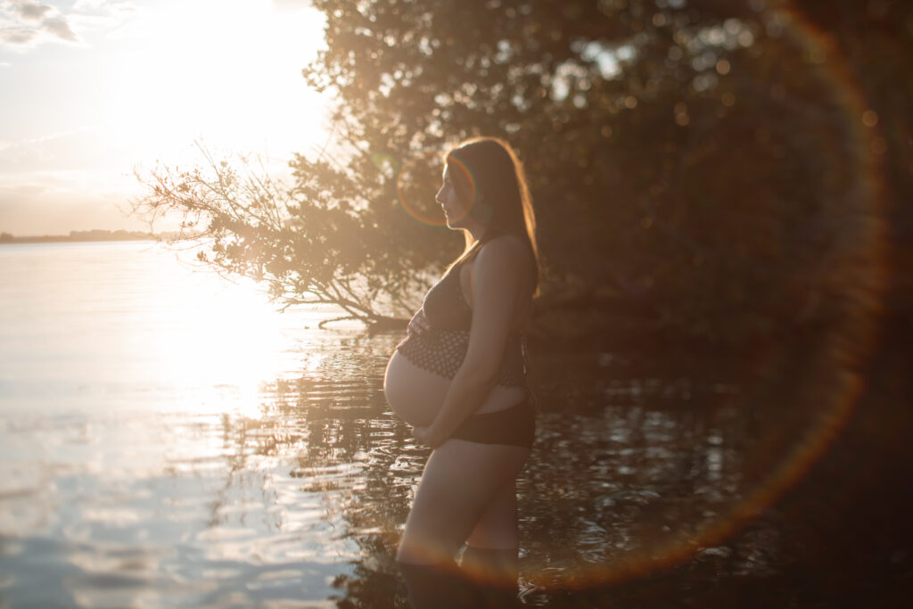 Expecting mother at sunset in the water, photographed by The Deans Photography.