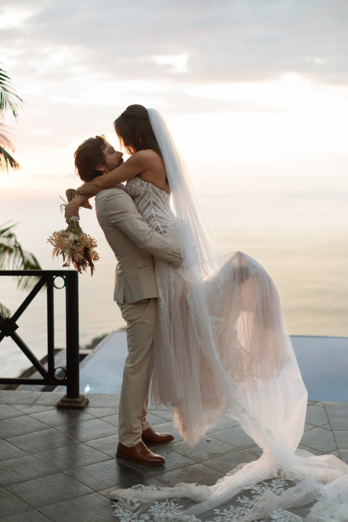 Romantic sunset wedding photo of a bride and groom with the Pacific Ocean in the background at Villa Caletas, Costa Rica, captured by The Deans Photography.