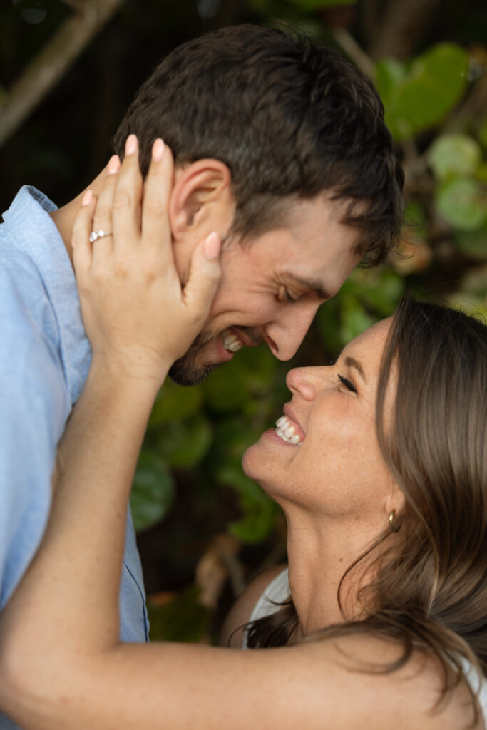 Candid close-up of an engaged couple laughing during a beach photo session.