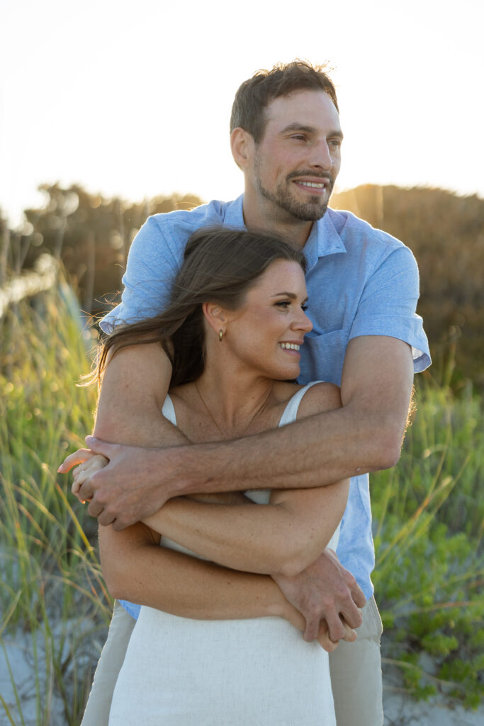 Engaged couple embracing near coastal sand dunes in Melbourne Beach.