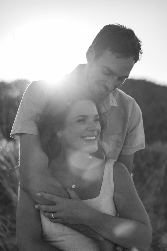 Engaged couple embracing near coastal sand dunes on the Space Coast.