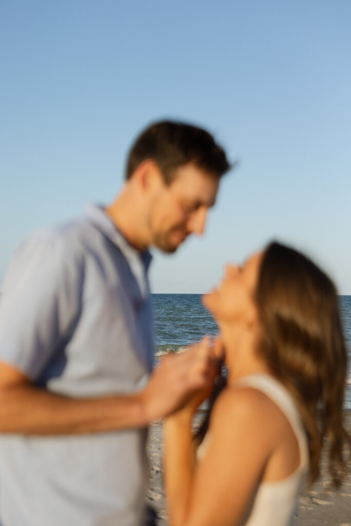 Silhouetted couple sharing a kiss during sunset on a Florida beach.