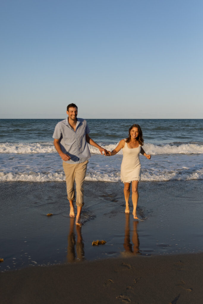 Engaged couple running on the sand watching the waves on the Treasure Coast.