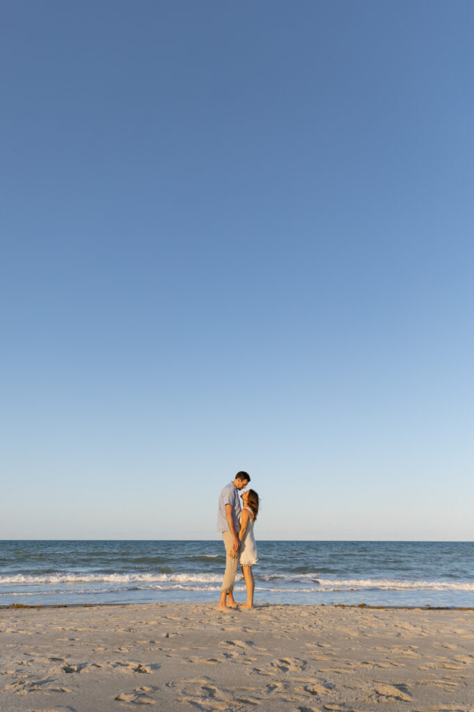 Couple walking hand in hand along the Treasure Coast shoreline during golden hour.