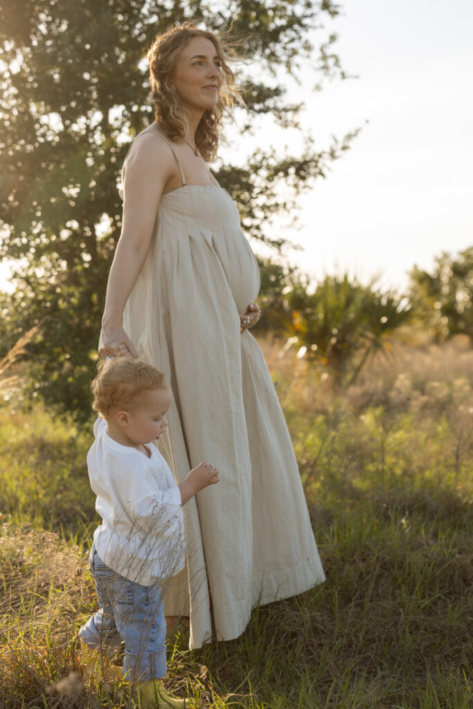 Mother wearing a neutral cream dress during golden hour motherhood session in Florida.