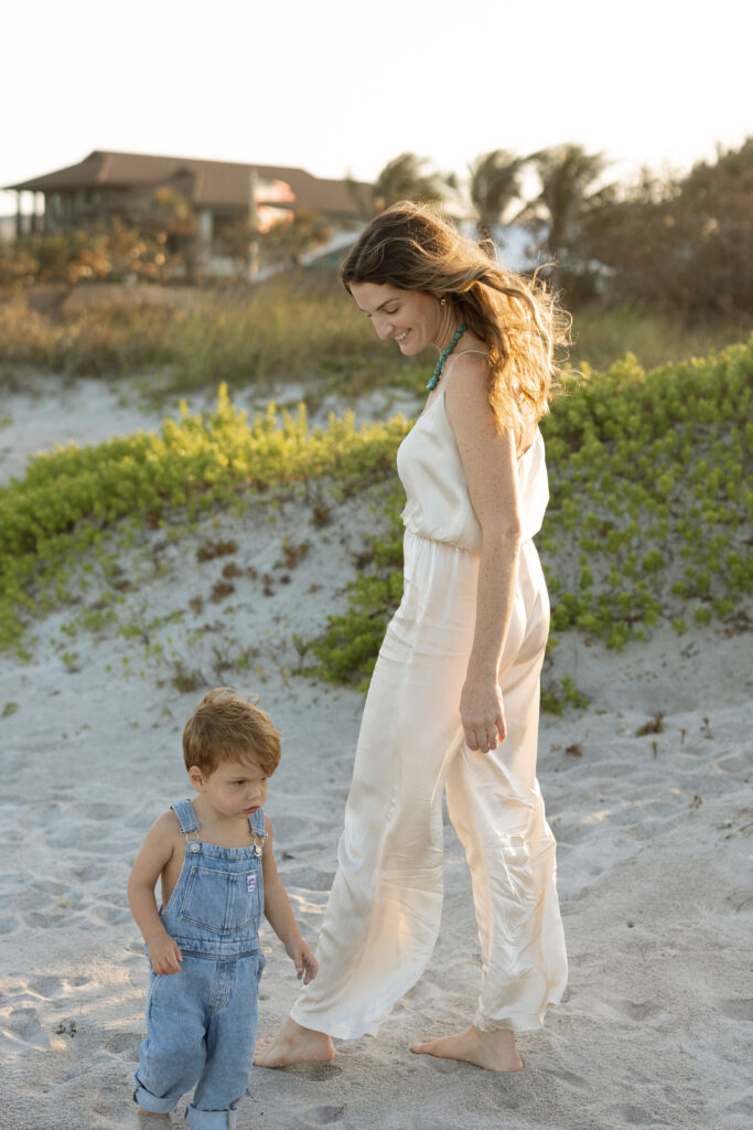 Minimalist motherhood photo with mother in neutral matching set with toddler on the beach.