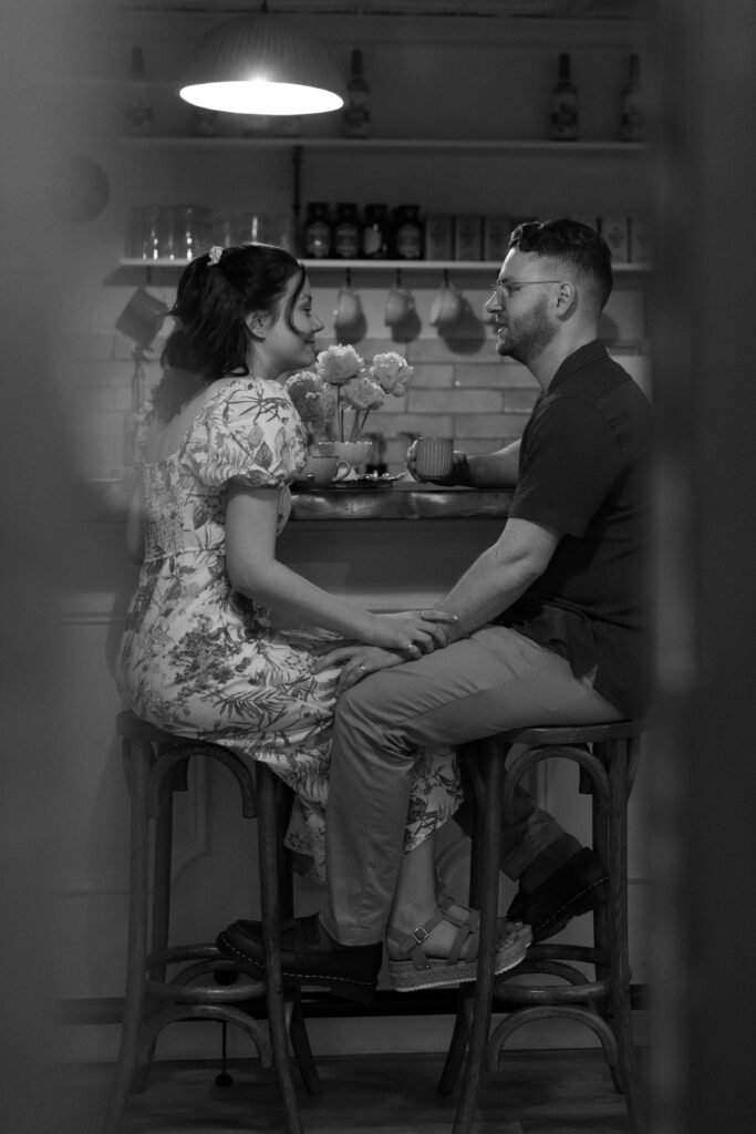 Cozy lifestyle engagement photos of a couple snuggling in a coffee shop