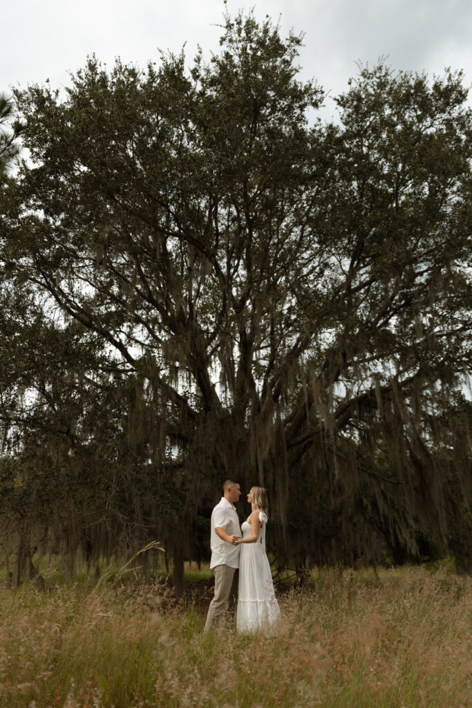 Couple holding hands under a mossy tree at Lake Louisa State Park engagement session in Central Florida.